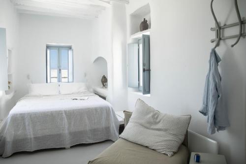 a white bedroom with a bed and a couch at DYO Tinos in Triandáros