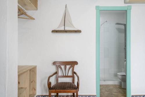 a wooden chair sitting in a bathroom next to a toilet at Hostal Santa Catalina in Conil de la Frontera