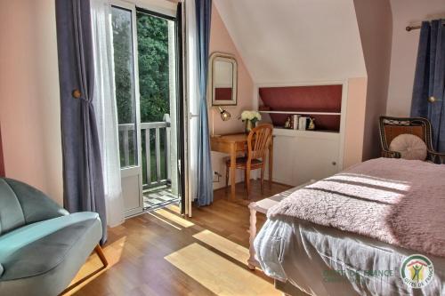 a bedroom with a bed and a desk and a window at L'orée du bois in Ploumagoar