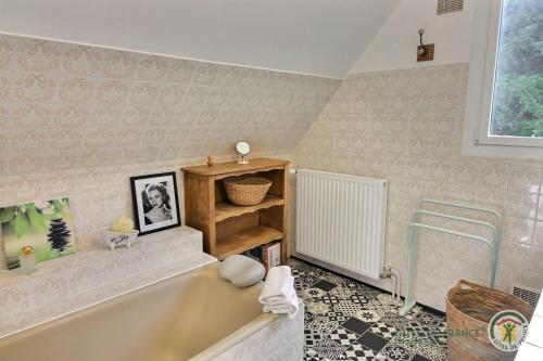a bathroom with a bath tub and a window at L'orée du bois in Ploumagoar