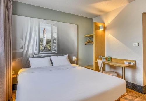 a hotel room with a large bed and a desk at B&B HOTEL Bordeaux Sud Mios 3 étoiles in Mios