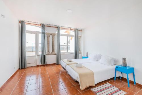 a bedroom with a white bed and a blue table at HI Évora – Pousada de Juventude in Évora