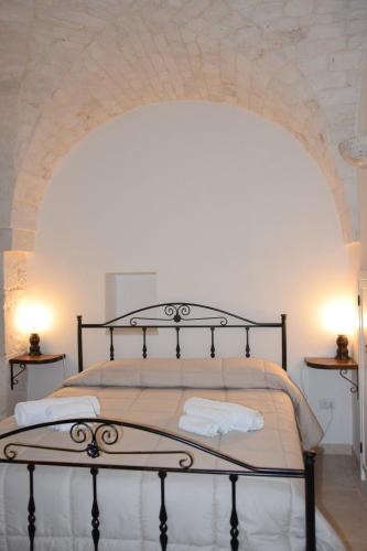 a bedroom with a large bed with a white wall at Dimora Domrose in Locorotondo