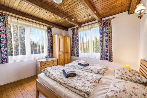 a bedroom with two beds and two windows at Chlúpka u Luisa in Telgárt