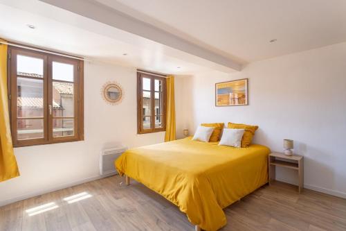 a bedroom with a bed with yellow sheets and windows at Suite du Soleil - Studio - Hypercentre in Narbonne