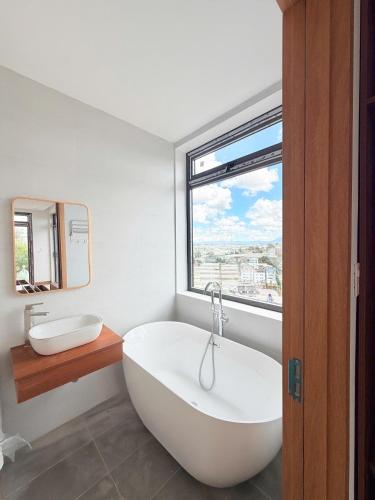a bathroom with a large white tub and a window at Enjoy Villa Da Lat in Khu Chi Lăng
