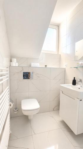 a white bathroom with a toilet and a sink at Hotel Evan u Hoffera with free parking in Topoľčany