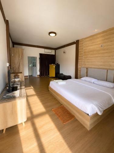 a bedroom with a large white bed and wooden floors at กัลยา รีสอร์ท in Ban Bang Saen (1)