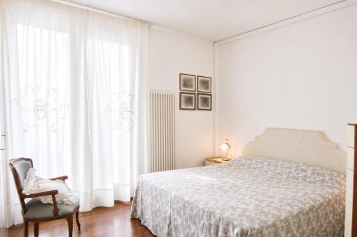 a white bedroom with a bed and a chair at Condominio Maria Ida in Caorle