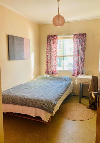 a bedroom with a bed and a desk and a window at Rosahuset in Kabelvåg