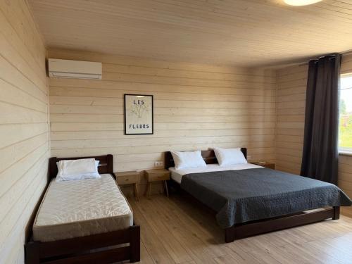 a room with two beds in a room with wooden walls at Тиха Хвиля in Gribovka