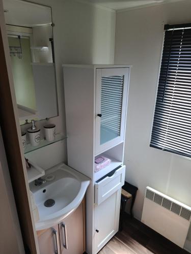 a white bathroom with a sink and a mirror at Le Deauville in Le Grau-dʼAgde