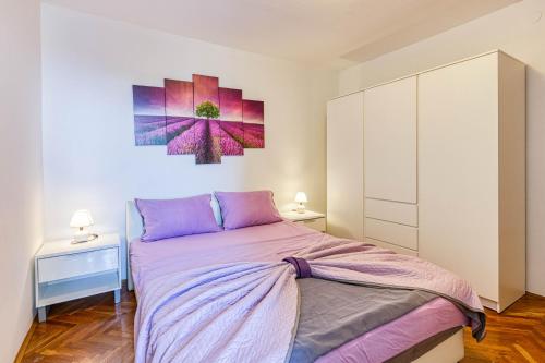 a bedroom with a bed and a painting on the wall at Apartman Doris in Lovran