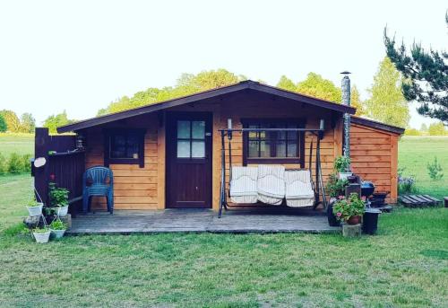 a cabin with a porch and chairs in the yard at SP camping Spāres Prieduļi in Nīca