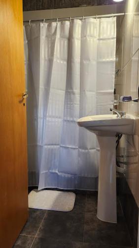 a bathroom with a white shower curtain and a sink at Cabañas Elementos in Huerta Grande
