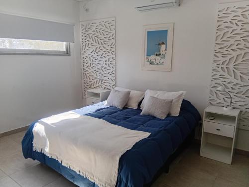 a bedroom with a bed with blue and white sheets at DOLCE LUNA in Roldán