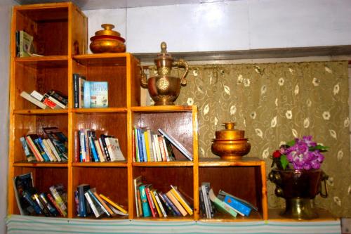 un estante de libros lleno de libros y un jarrón de flores en Himalayan Lodge, en Nāmche Bāzār