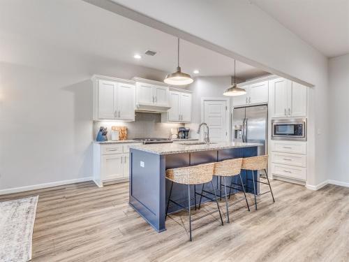 a kitchen with white cabinets and a blue island at Kingsport Modern Oasis in Broken Arrow