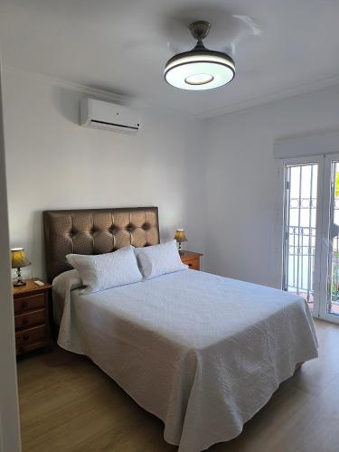 a white bedroom with a large bed with a brown headboard at Casa Torrox Costa cerca del mar in Torrox