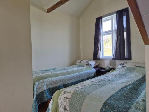 two beds in a room with a window at Steinhúsið in Hólmavík