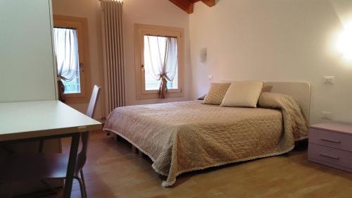 a bedroom with a bed and a desk and two windows at Boschetto di Campagna in Castagnole