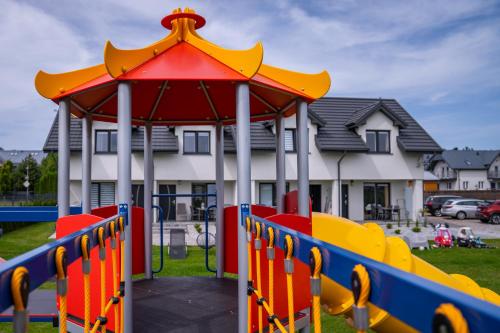a playground with a gazebo in front of a house at Apartamenty Lagos in Karwia