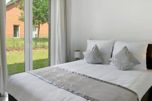 a white bed with pillows in front of a window at Auszeit in der Heide mit Terrasse in Bienenbüttel