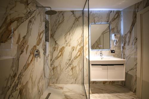 a bathroom with a shower and a sink and a mirror at Comfort Boutique Hotel in Tirana