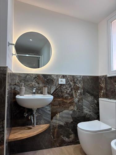 a bathroom with a sink and a toilet and a mirror at Amarè House in Catania