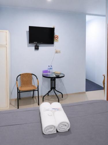 a room with a table and a tv and two towels at NamRoom at Jatiwaringin in Jakarta