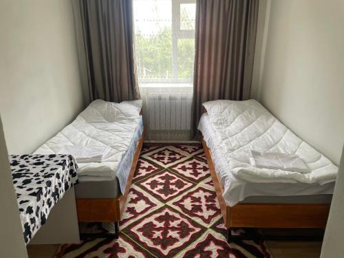 two beds in a room with a window at Kutbi Guest House in Bokonbayevo