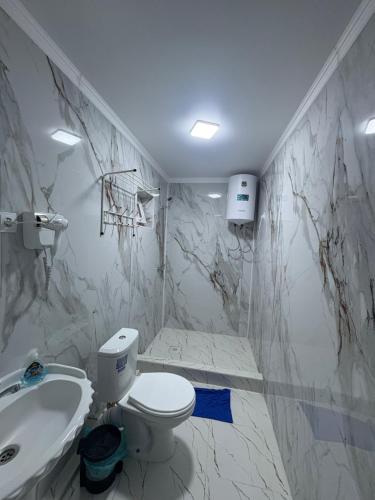 a white bathroom with a toilet and a sink at Guest House Nurdana in Tossor