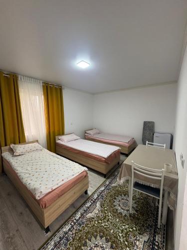 a room with three beds and a desk and a table at Guest House Nurdana in Tossor