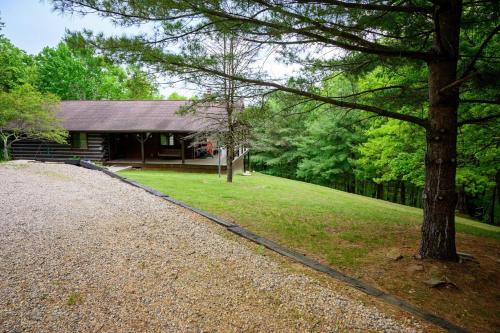 a log cabin with a tree and a gravel driveway at Moonlight Ridge in Laurelville
