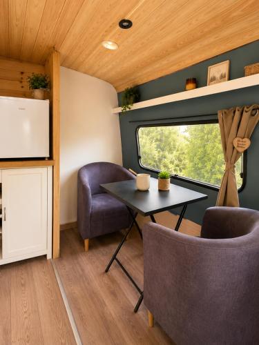 a room with a table and two chairs and a window at La caravane du Farfadet in Flangebouche