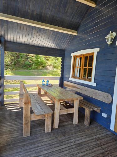 a wooden picnic table and a bench on a deck at Niebieski domek na Kaszubach in Dziemiany