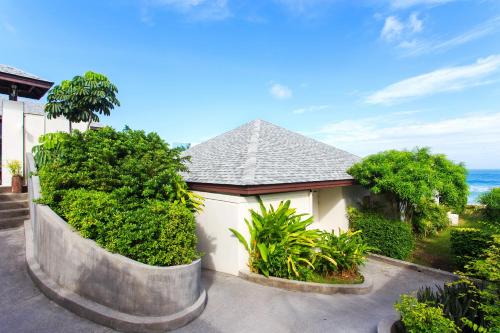 a house with bushes and trees in front of the ocean at Samui Resotel Beach Resort in Chaweng
