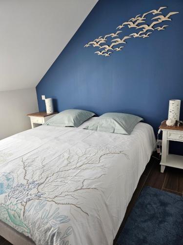 a bedroom with a bed with a blue wall at Cap à l'ouest in Saint-Benoît-des-Ondes