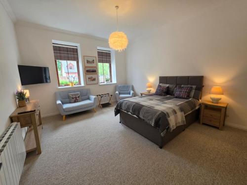 a bedroom with a bed and a couch and a chair at Single Malt Apartment in the old distillery in Inverlochy