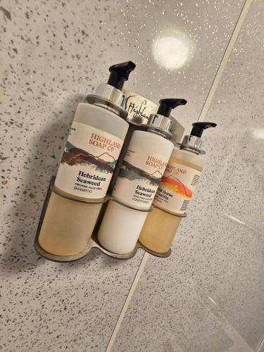 a group of four shampoo bottles sitting on a counter at Single Malt Apartment in the old distillery in Inverlochy