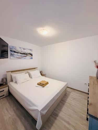 a bedroom with a white bed with a wooden floor at Apartament Alfa Saturn in Saturn