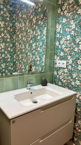 a bathroom with a sink and flowers on the wall at Alegría 2 in Amés