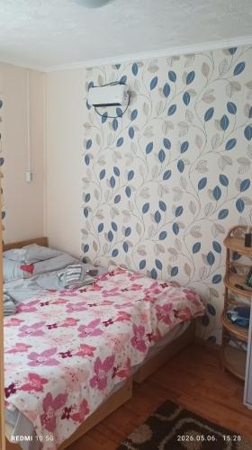 a bedroom with a bed with a floral patterned wall at Fa-mìlia Vendègház in Tiszavasvári
