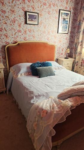 a bed in a bedroom with pink wallpaper at Chambre d'hôtes Le Havre in Saint-Coulomb