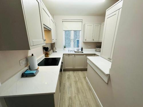 a white kitchen with white cabinets and a sink at Stay 55 in Peebles