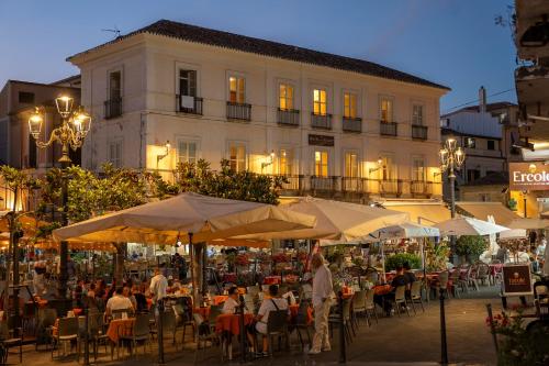 a group of people sitting at tables in front of a building at Hotel della Piazza in Pizzo