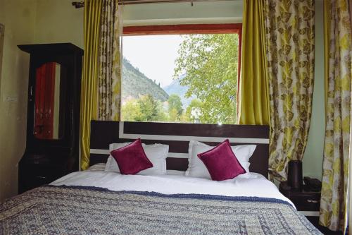 a bed with purple pillows in front of a window at Samoon Guest House Sonmarg in Kulan