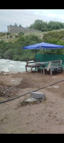 a picnic table with a blue umbrella and chairs at Дача in Vorontsovskoye
