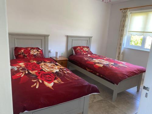 a bedroom with two beds with red sheets and roses at Sunrise House in Cahersiveen