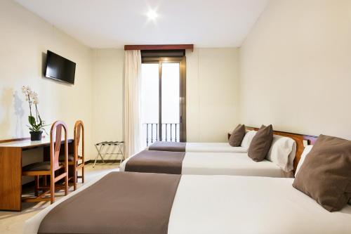 a hotel room with two beds and a desk at Hotel Condal in Barcelona